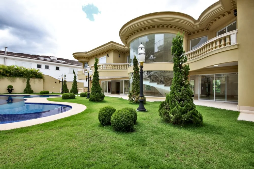 Residência Alphaville com fachada contemporânea, grandes panos de vidro e jardim integrado